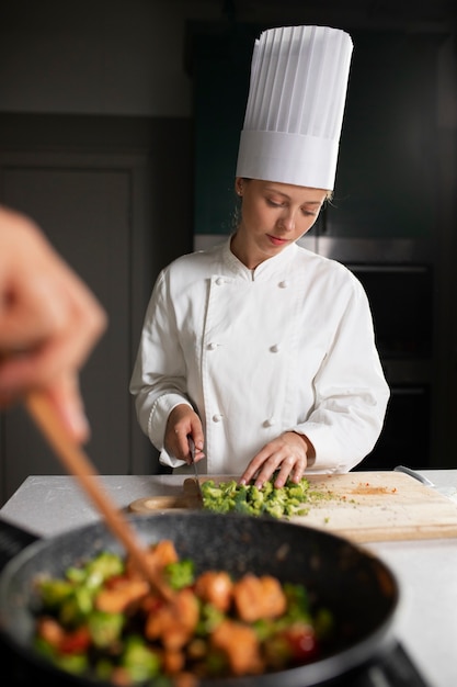 Бесплатное фото Женщина, вид спереди, готовит на кухне