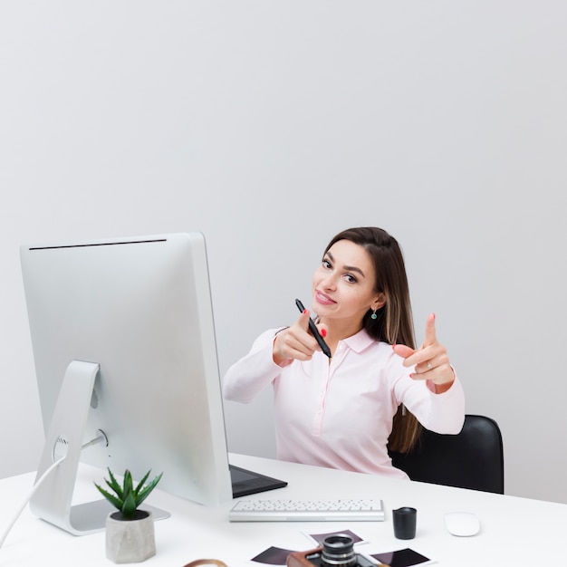 Front view of woman at desk giving thumbs up