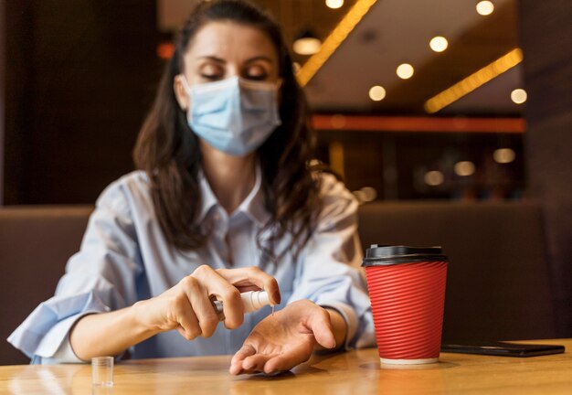 Front view woman disinfecting her hands in a restaurant