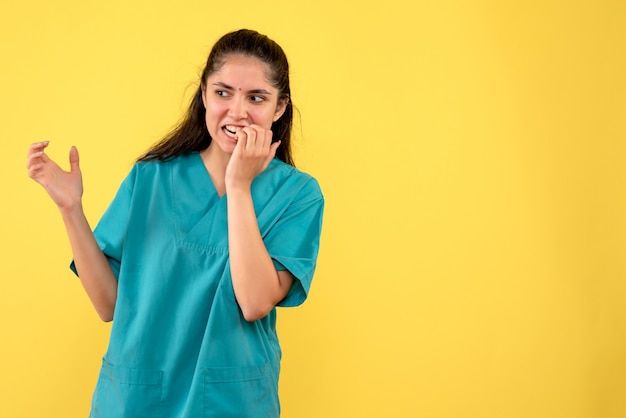 Foto gratuita vista frontale del medico della donna in uniforme che mette le mani sulla sua bocca sulla parete gialla