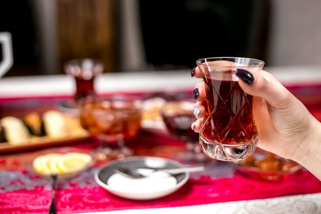 Front view a woman drinks tea from an armudu of a glass