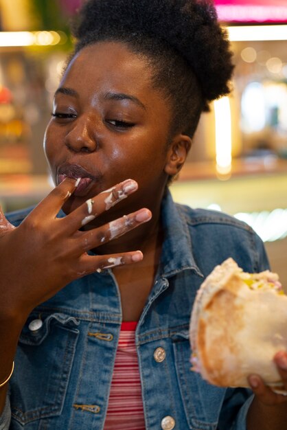 Front view woman eating burger in a funny way