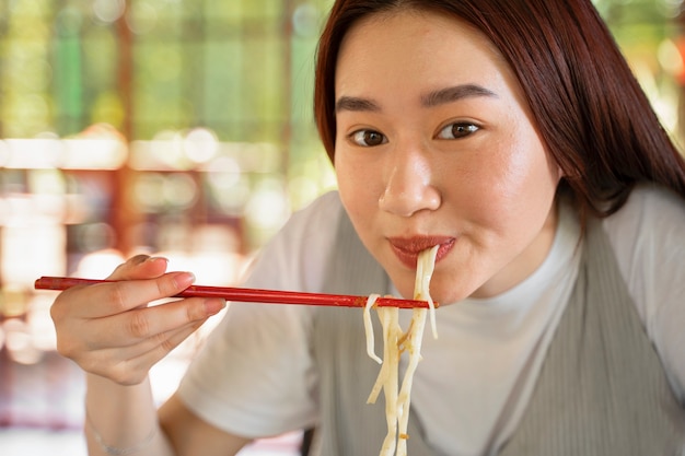 Front view woman eating noodles