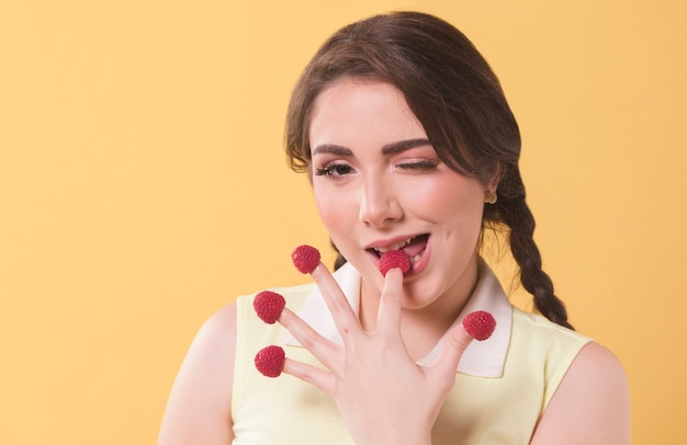 Free photo front view of woman eating raspberries off her fingertips and winking