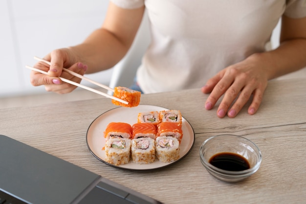 Foto gratuita donna di vista frontale che mangia sushi a casa