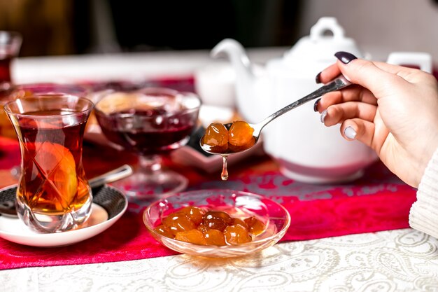Front view woman eating white cherry jam with tea
