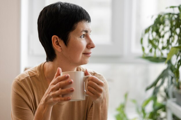 Front view of woman enjoying a drink in mug