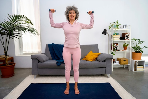 Foto gratuita donna di vista frontale che si esercita con i dumbbells