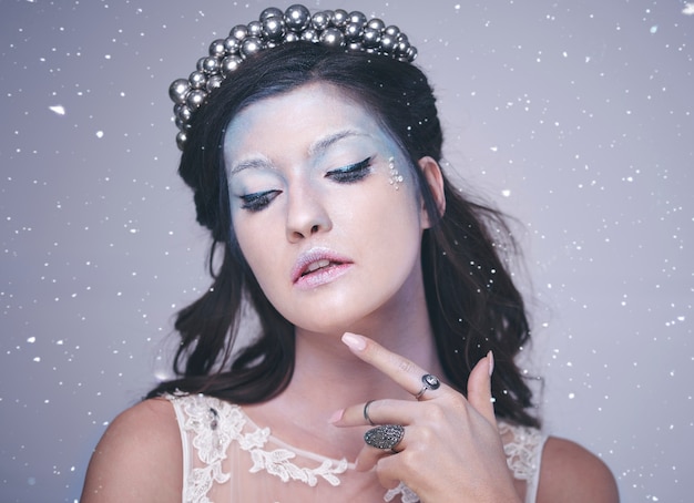 Front view of woman in frosty make up among snow falling  
