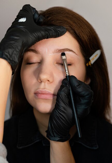 Front view of woman getting an eyebrow treatment from specialist