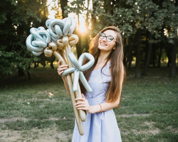 Free photo front view woman holding balloons in sunlight