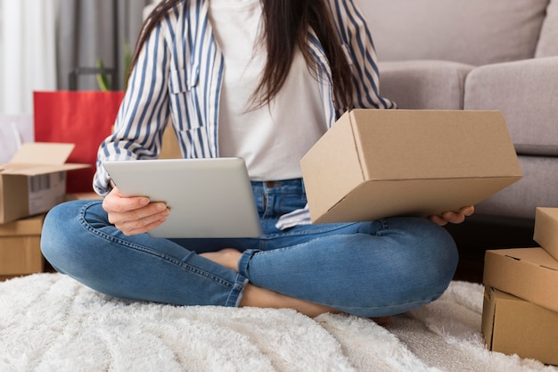 Front view woman holding a box and a tablet