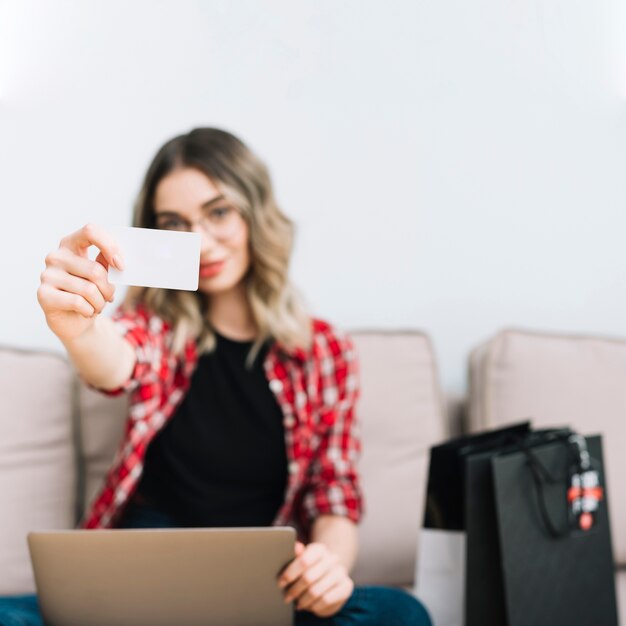 Front view woman holding card while sitting on couch