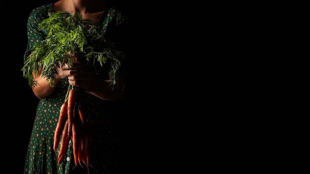 Front view woman holding carrots with copy-space