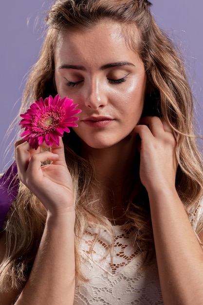 Front view of woman holding a chrysanthemum near her face