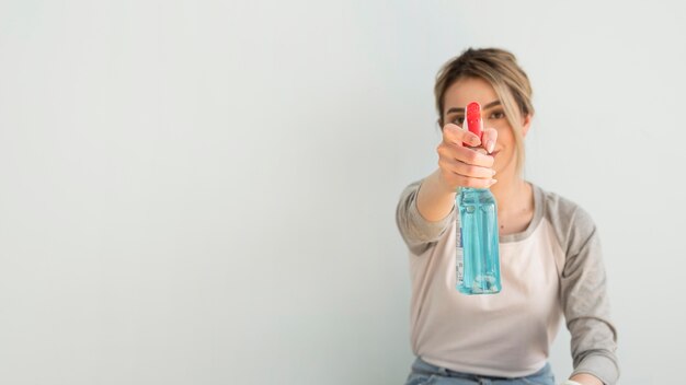 Free photo front view of woman holding cleaning solution with copy space