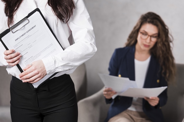 Front view of woman holding contract and another one reading papers