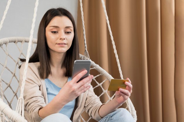 Front view of woman holding credit card and smartphone