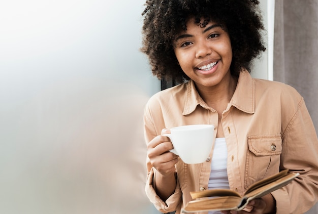 Free photo front view woman holding a cup of coffee and a book