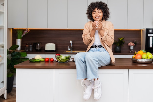 Foto gratuita donna di vista frontale che tiene una tazza di caffè in cucina