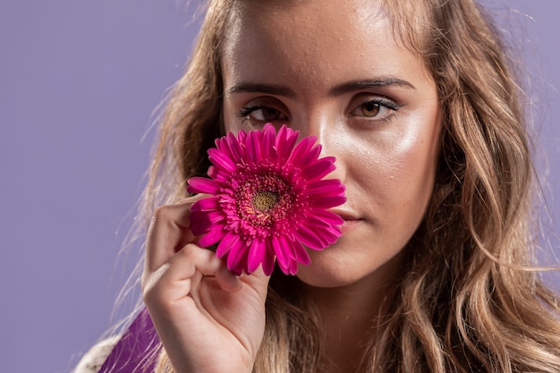 Foto gratuita vista frontale della donna che tiene un fiore vicino al suo fronte