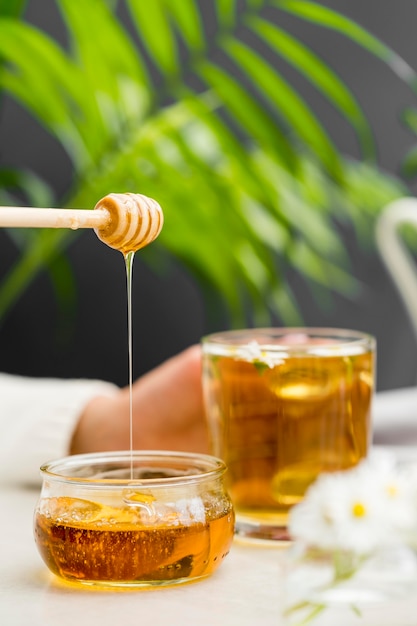 Front view woman holding glass with tea and honey dipper