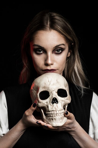Front view of woman holding human skull