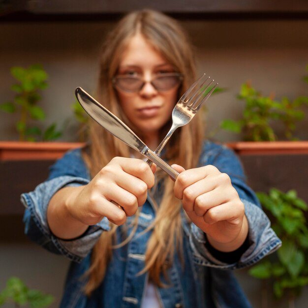 Front view of woman holding knife and fork in an x