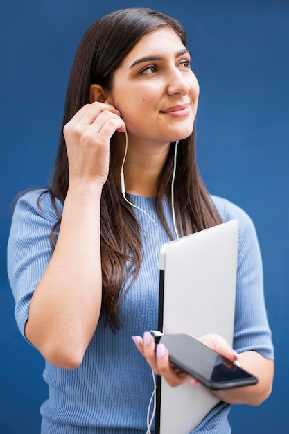 Free photo front view of woman holding laptop and listening to music on earphones