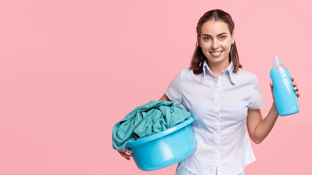 Front view woman holding laundry basket and detergent