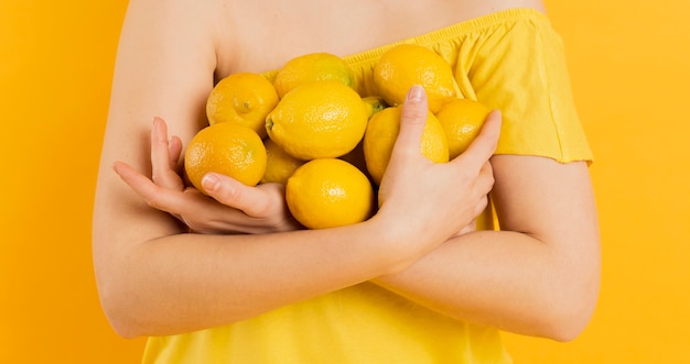 Front view of woman holding lemons in her arms