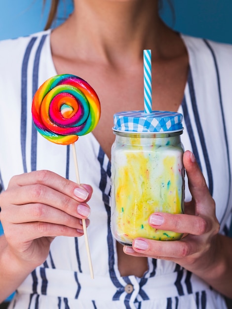 Front view of a woman holding milkshake and lollipop