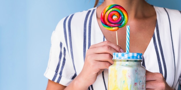 Front view of a woman holding a milkshake and lollipop