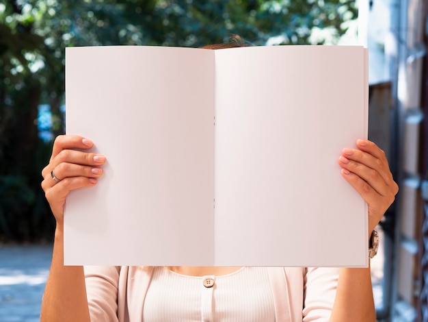 Free photo front view woman holding a mock-up magazine