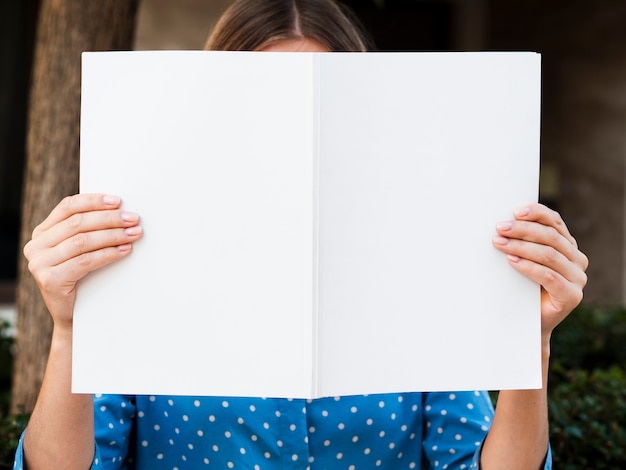 Free photo front view woman holding a mock-up magazine