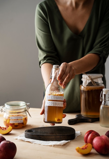 Front view woman holding nectarine kombucha