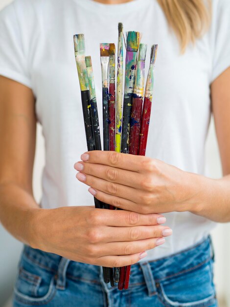 Front view of woman holding paint brushes in hands