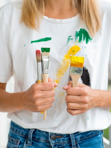 Front view of woman holding paint brushes