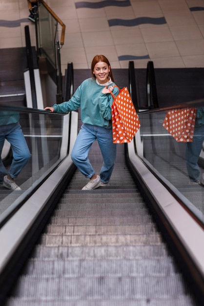 Front view woman holding paper bag on escalator