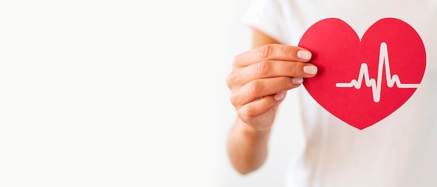 front view of woman holding paper heart with heartbeat