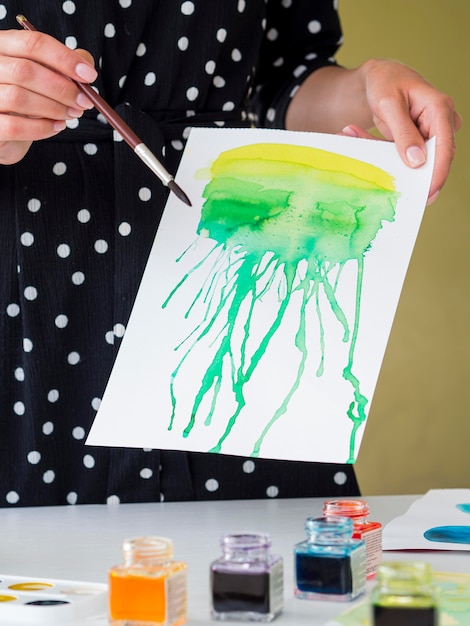 Front view of woman holding paper with watercolor