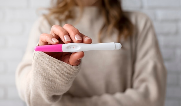 Front view woman holding positive pregnancy test