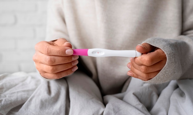 Foto gratuita donna di vista frontale che tiene test di gravidanza positivo