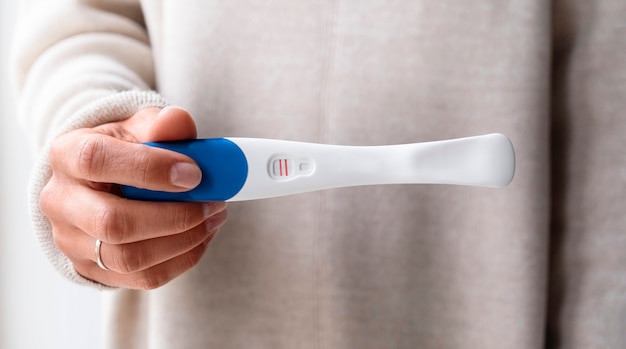 Free photo front view woman holding positive pregnancy test