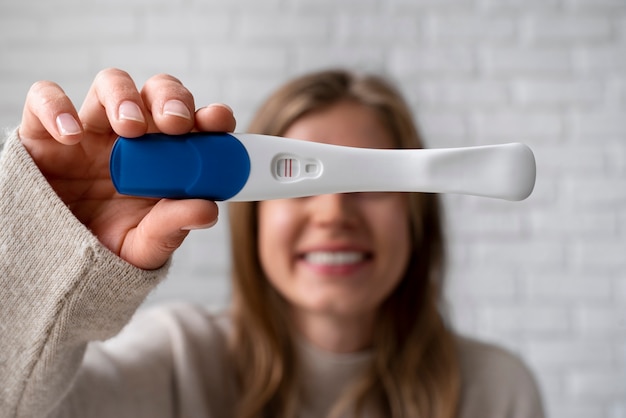 Front view woman holding positive pregnancy test