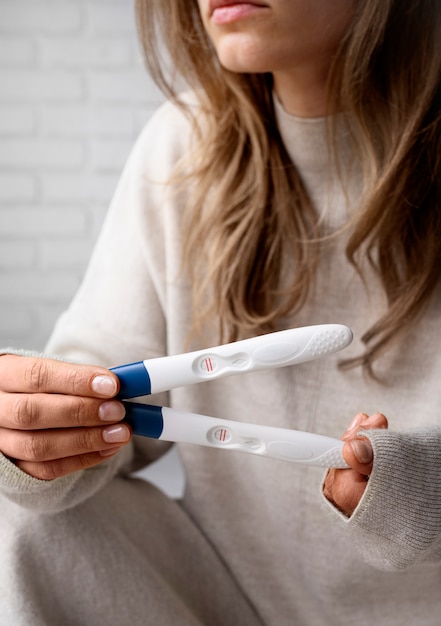 Front view woman holding positive pregnancy tests