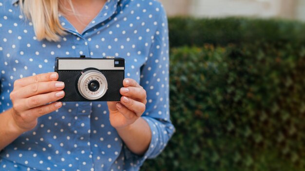 Front view woman holding a retro photo camera