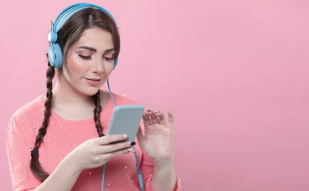 front view of woman holding smartphone and listening to music on headphones