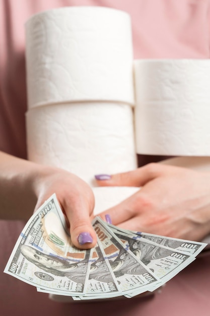 Front view of woman holding toilet paper rolls and handing money