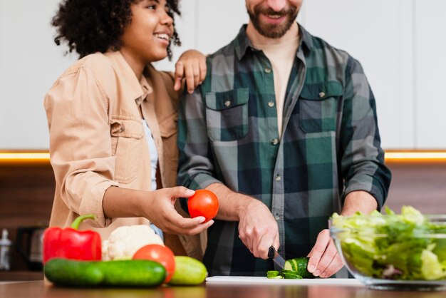 Женщина вид спереди держит помидор и мужчина нарезка овощей